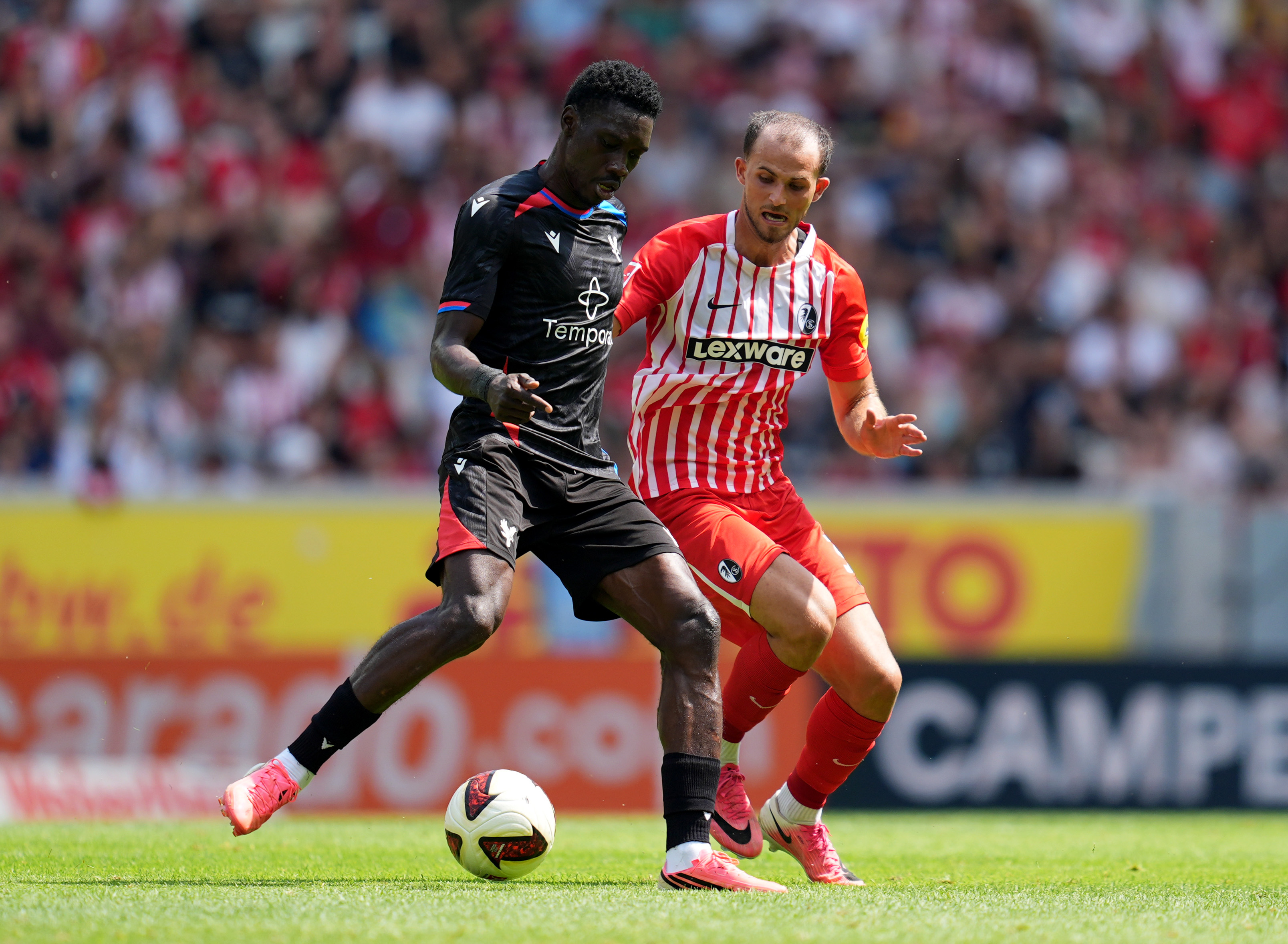 FREIBURG IM BREISGAU, GERMANY - AUGUST 15: Ismaila Sarr of Crystal Palace is challenged by Max Rosenfelder of SC Freiburg during the pre-season friendly match between Sport-Club Freiburg and Crystal Palace at Europa-Park Stadion on August 15, 2026 in Freiburg im Breisgau, Germany.