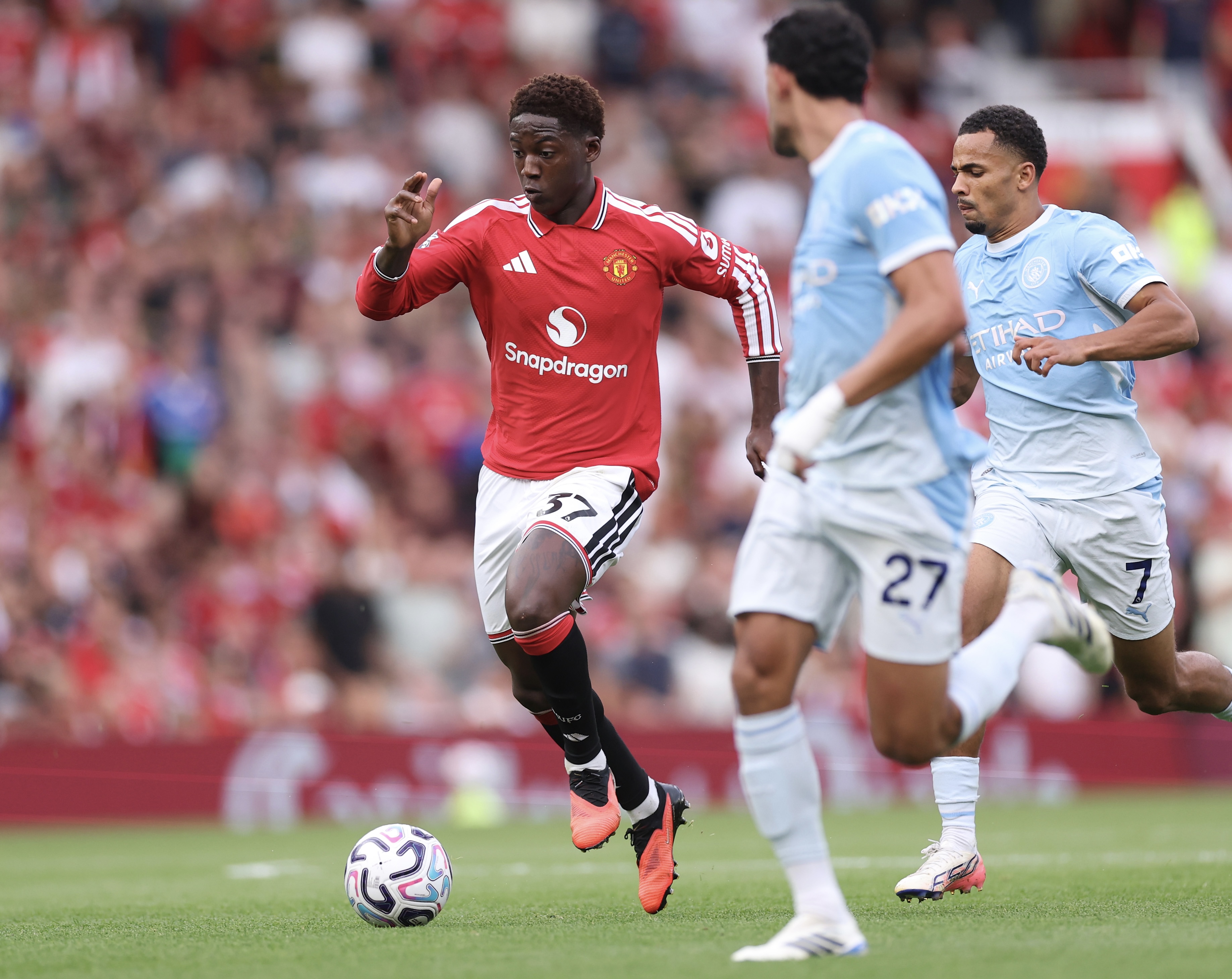MANCHESTER, ENGLAND - SEPTEMBER 13: Kobbie Mainoo of Manchester United runs with the ball under pressure from Iliman Ndiaye of Manchester City during the Premier League 2026/27 match between Manchester United and Manchester City at Old Trafford on September 13, 2026 in Manchester, England. (Photo by Carl Recine/Getty Images)